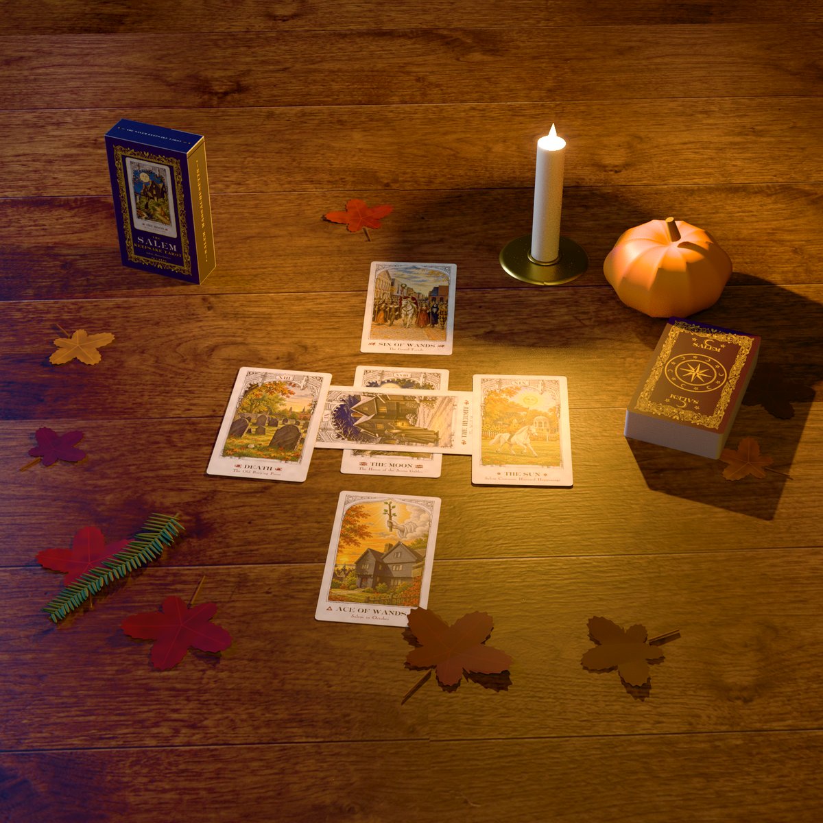 A spread of Salem Keepsake Tarot cards by candlelight on an old wooden table, with the tuck box, the deck, a small pumpkin and autumn leaves